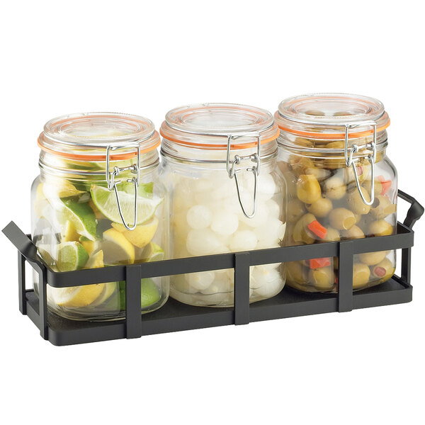 A black metal rack holding three glass jars of limes.