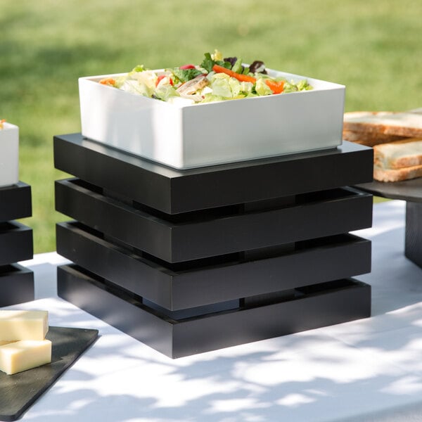 A black square Cal-Mil bamboo crate riser with a salad on a table.