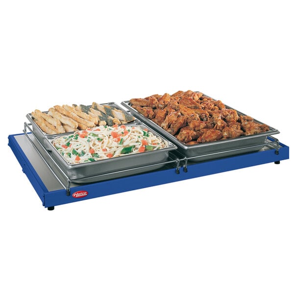 A Hatco heated shelf with trays of food on a table.