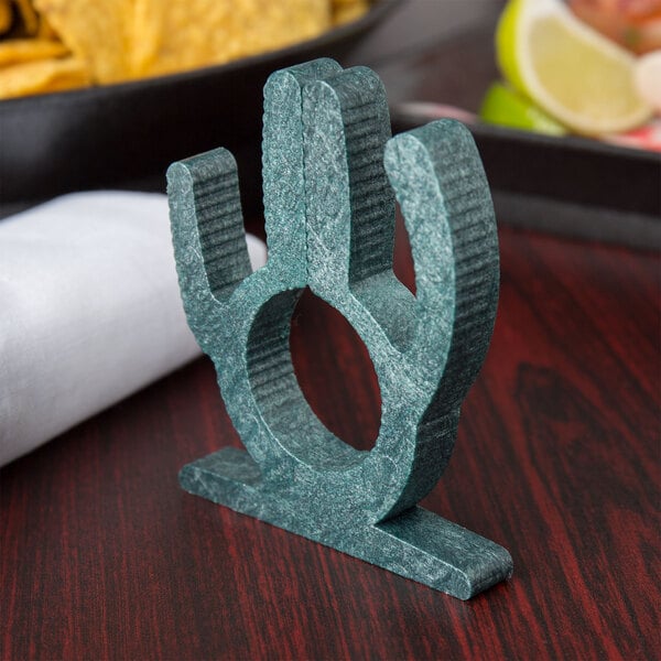 A green HS Inc. cactus napkin holder on a table.