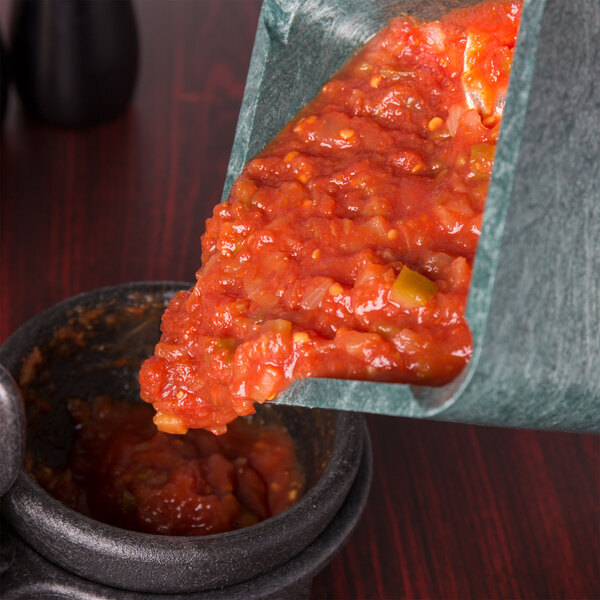 A HS Inc. jalapeno pitcher filled with salsa being poured into a bowl.