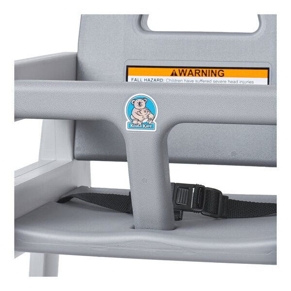 A Koala Kare gray plastic high chair with a warning label.