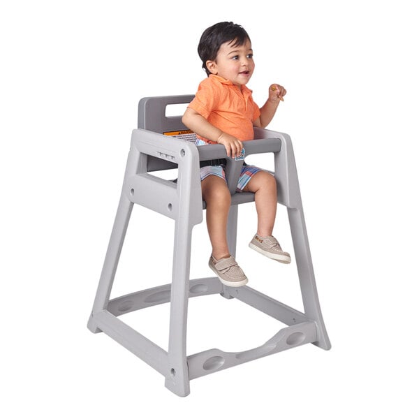 A child sitting in a Koala Kare gray plastic high chair with a toy.