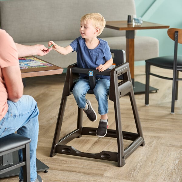 A brown stackable plastic high chair with a child seated in it at a restaurant table.