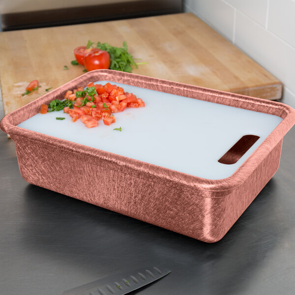 A metal tote with chopped tomatoes in a white liquid on a counter.