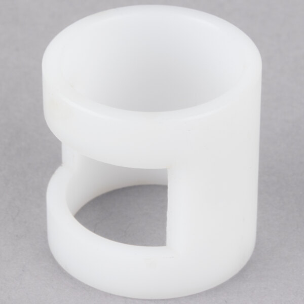A close-up of a white plastic slotted bushing with a hole in it.