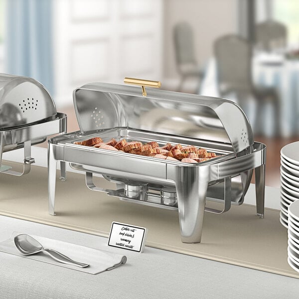 An Acopa Supreme gold accent roll top chafer on a buffet table with food and silverware.