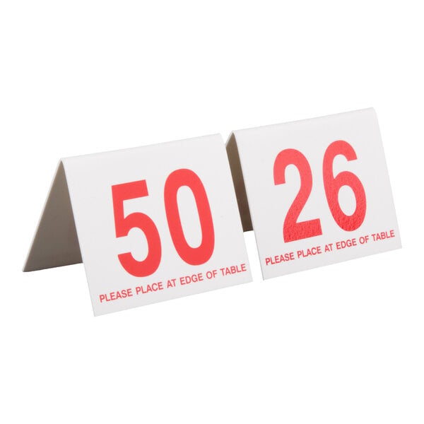 Two white, tent-shaped table signs with large red numbers '50' and '26' and the text 'PLEASE PLACE AT EDGE OF TABLE' printed below the numbers.