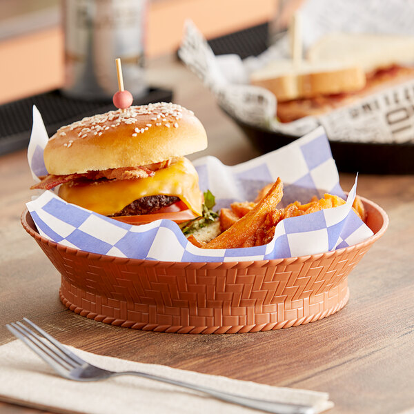 A terracotta plastic round basket filled with a cheeseburger and fries.