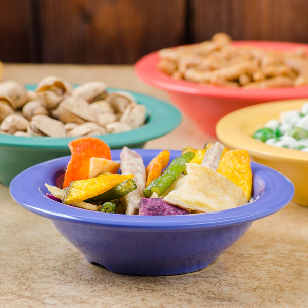 A table with a group of peacock blue Diamond Mardi Gras melamine bowls filled with colorful food.
