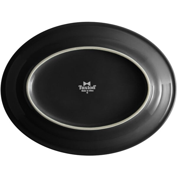 A black Tuxton oval china platter with a white rim.