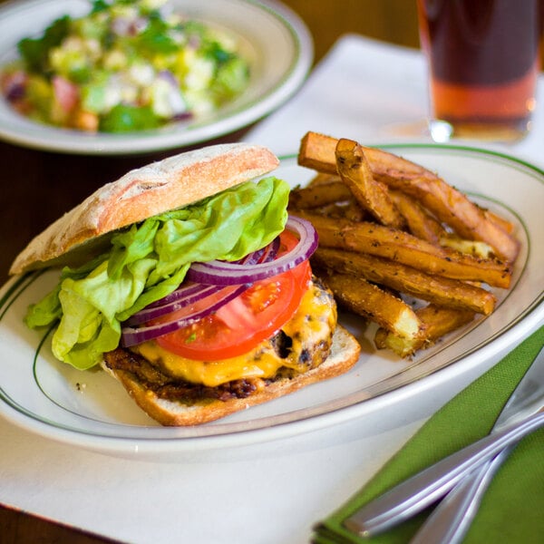 A Tuxton oval china platter with a burger and fries on it.