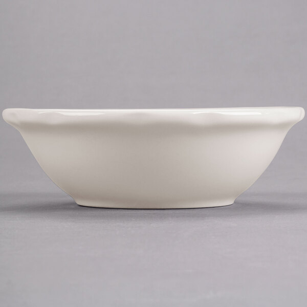 A white bowl with a scalloped edge on a gray surface.