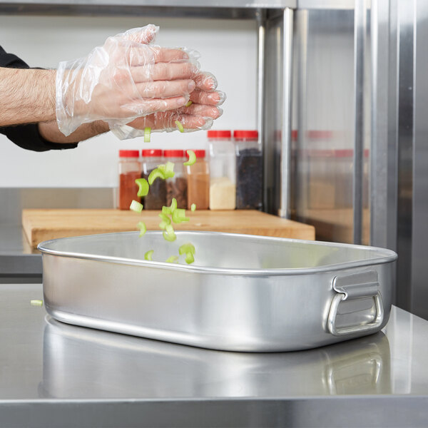 a silver pan with green vegetables falling into it
