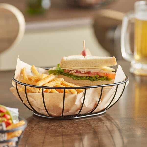 An American Metalcraft straight-sided basket with a sandwich and fries on a table.