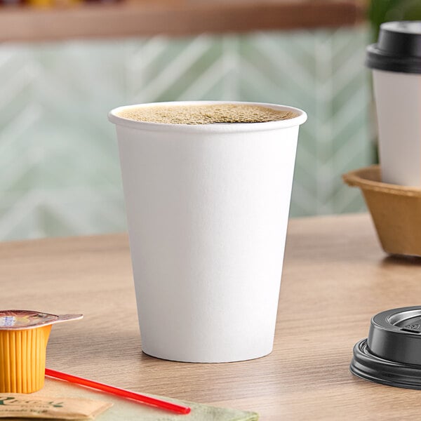 A white Choice paper hot cup filled with brown liquid on a table.