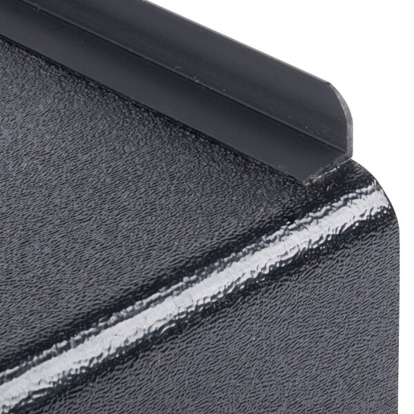 A close-up of a black metal surface with a rubber floor.