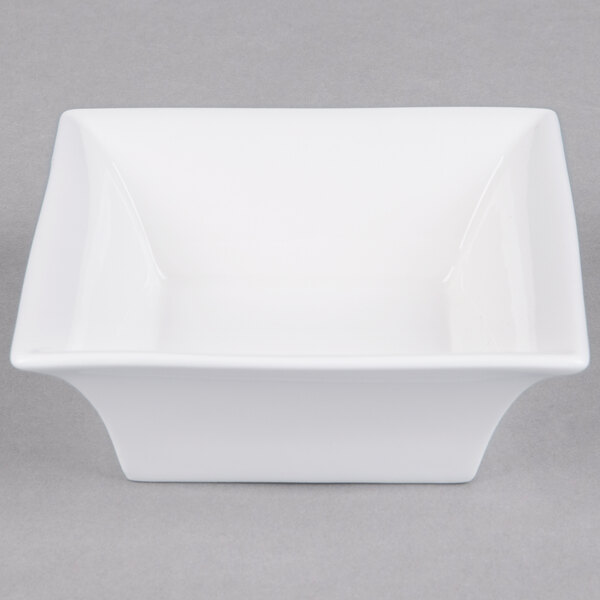 An Arcoroc white square bowl with a curved edge.