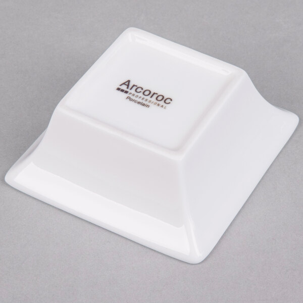 A white square Arcoroc flared bowl with black text.