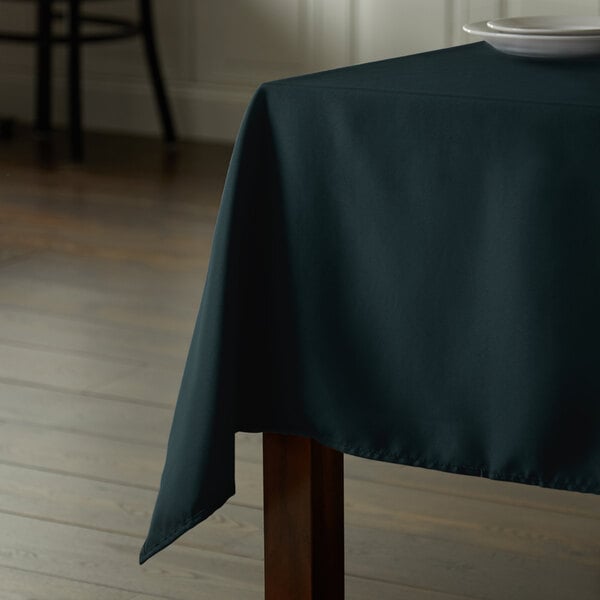 A rectangular hunter green Intedge table cover on a table with a white plate on it.