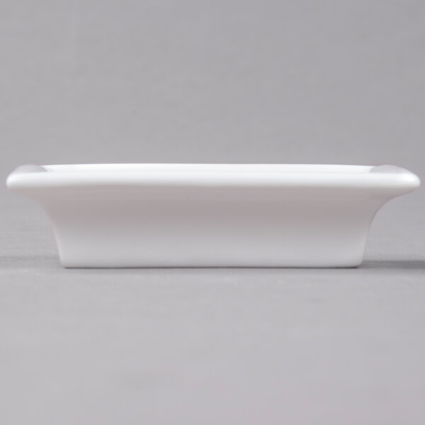An Arcoroc white rectangular bowl with a small handle on a gray surface.