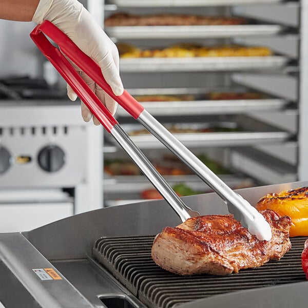 A person using Vollrath Jacob's Pride tongs to serve a piece of meat.