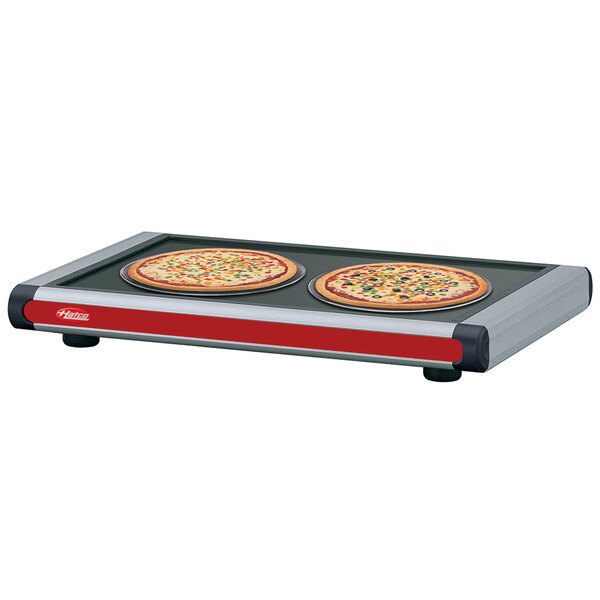 A Hatco heated shelf with black caps holding a pizza pan with two pizzas.