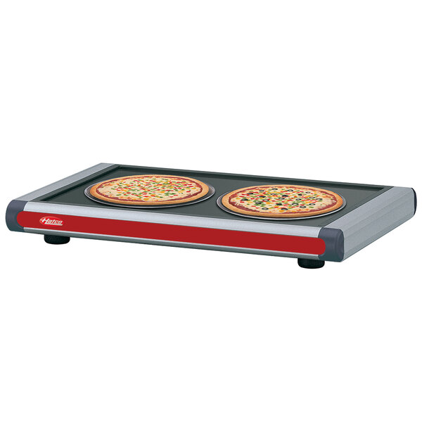 Two pizzas on a Hatco heated shelf with dark gray caps.