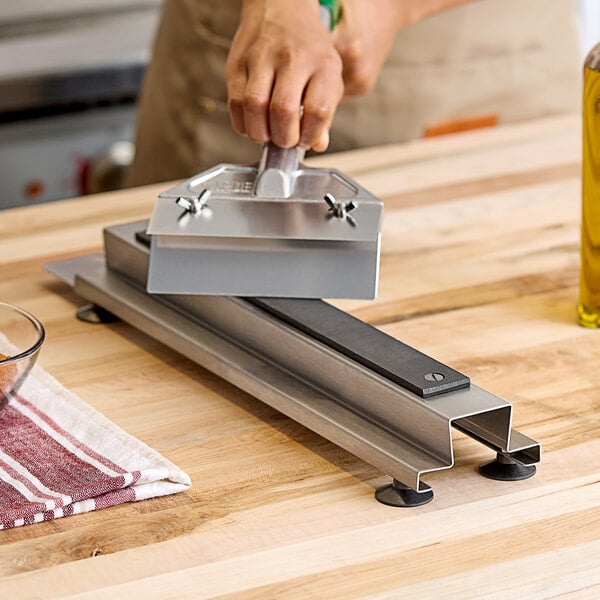 A hand using an Edlund griddle scraper sharpener to sharpen a blade.