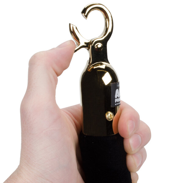A hand holding a black metal hook with brass ends.