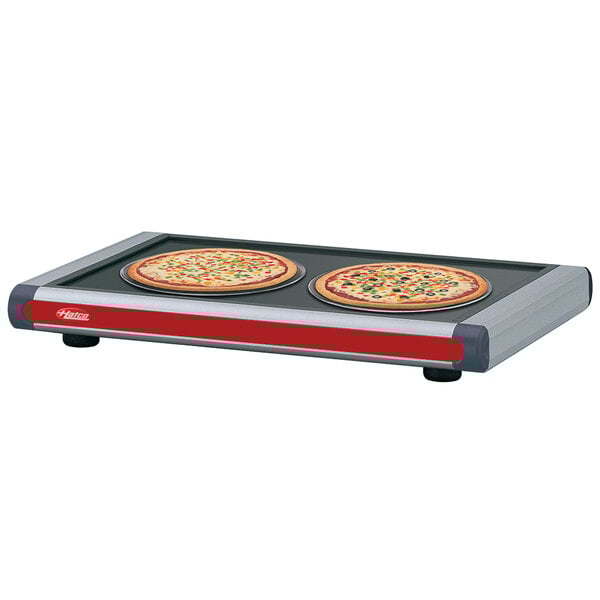 A Hatco heated shelf with pizzas on a pan.