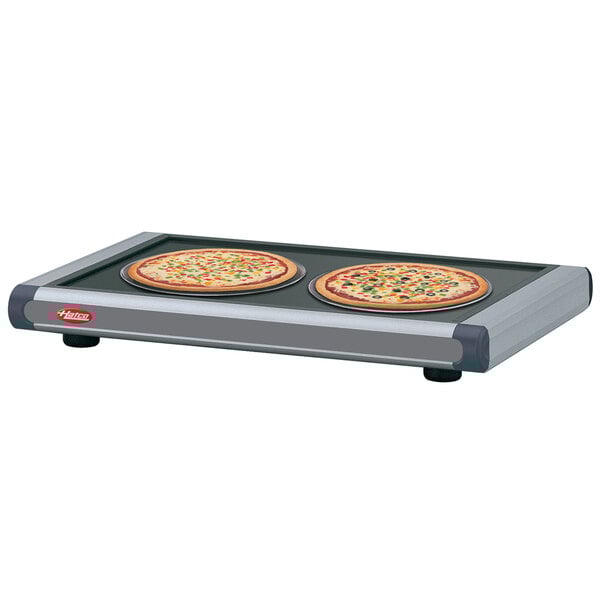 A Hatco heated shelf with pizza pans holding pizzas on a table.