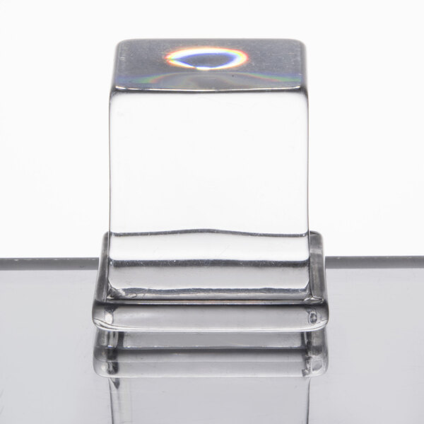 A clear glass container of medium ice cubes on a white surface.