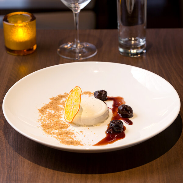 A white shallow coupe bowl with dessert on a table.