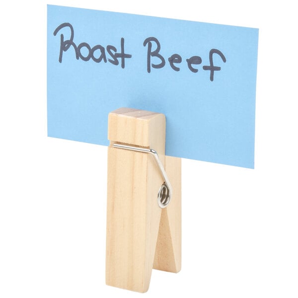 An American Metalcraft natural wooden clothespin table card holder with a blue card clipped to it.