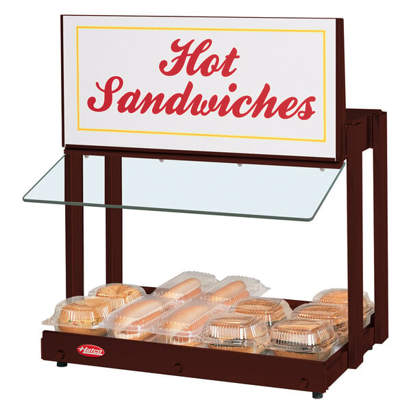 A Hatco countertop warmer with hot sandwiches and a sign.