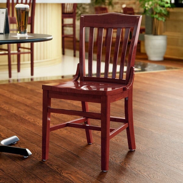 A Lancaster Table & Seating mahogany wood school house chair in a restaurant dining room.