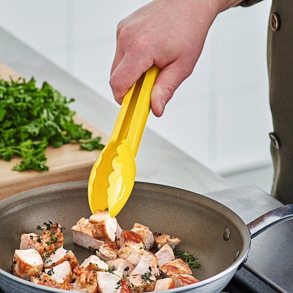 A person using yellow Mercer Culinary tongs to serve food