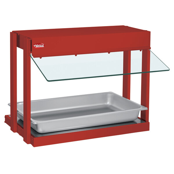 A Hatco red metal mini-merchandising warmer with a tray of food on a glass shelf.