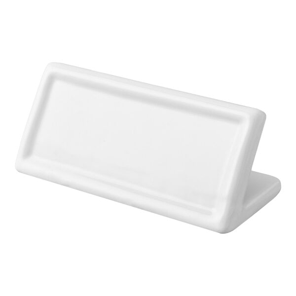 A white, rectangular ceramic object with a slanted surface and raised border, resembling a blank card holder or sign.