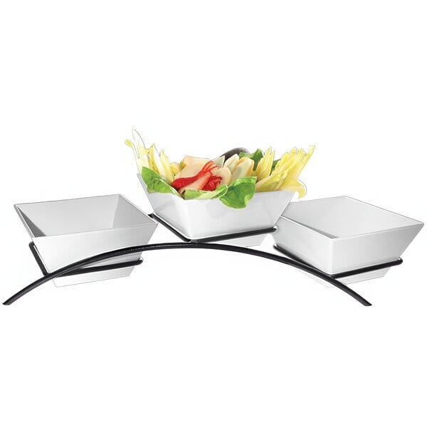 A black metal Cal-Mil arch stand with three square bowls of food.