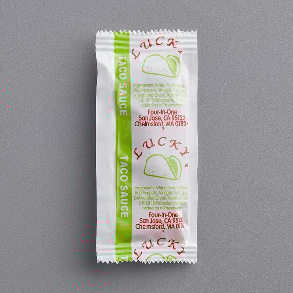 A close-up of a Taco Sauce portion packet.