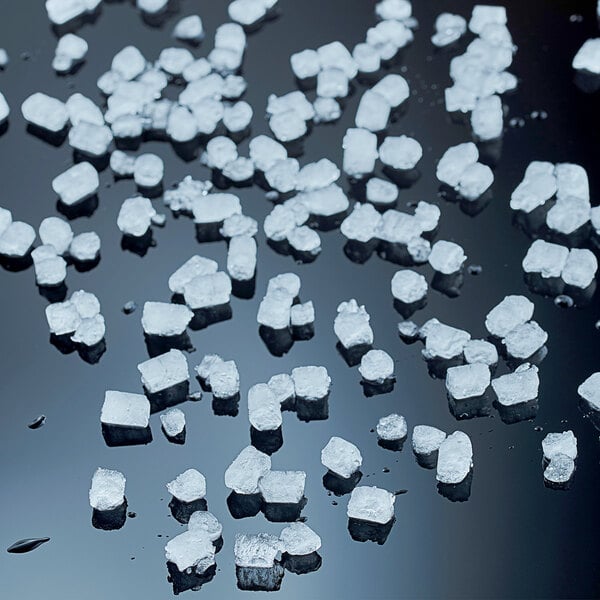 A collection of square ice cubes scattered on a reflective black surface.