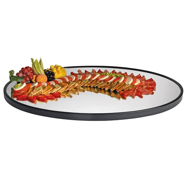 A Cal-Mil oval mirror tray with a raised black rim holding a plate of food on a table.