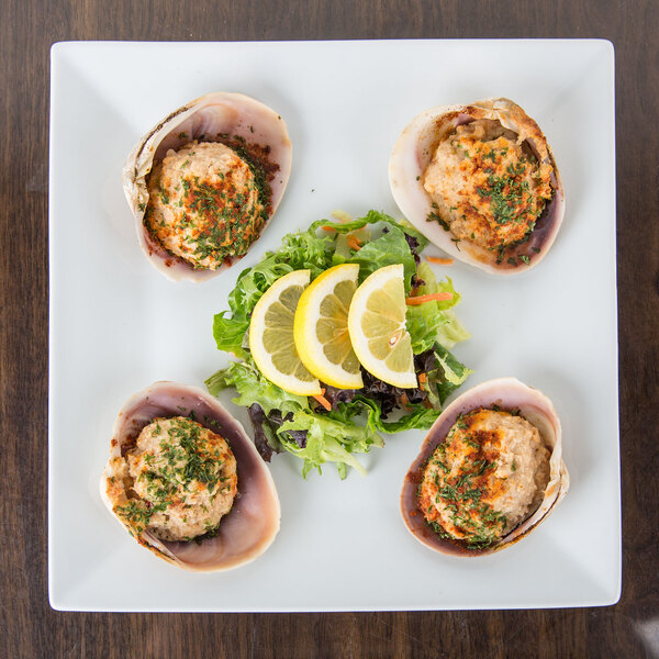 A Cal-Mil porcelain platter with food including clams and lemon slices on a table.