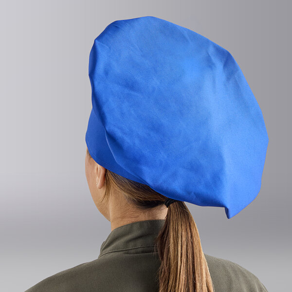 A royal blue 13-inch chef hat worn by a person with a ponytail.