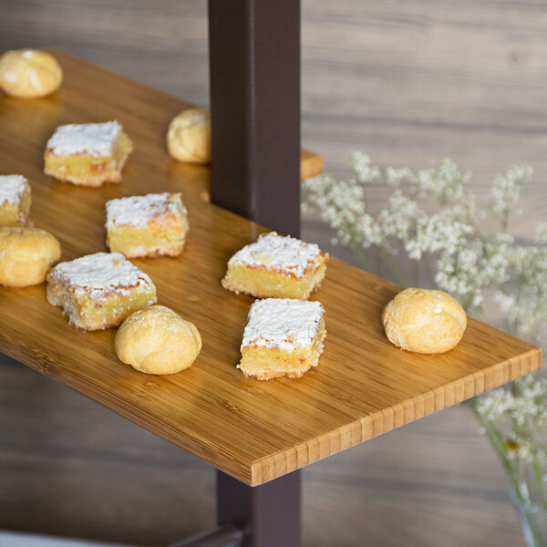 A Cal-Mil bamboo shelf with small pastries on it.