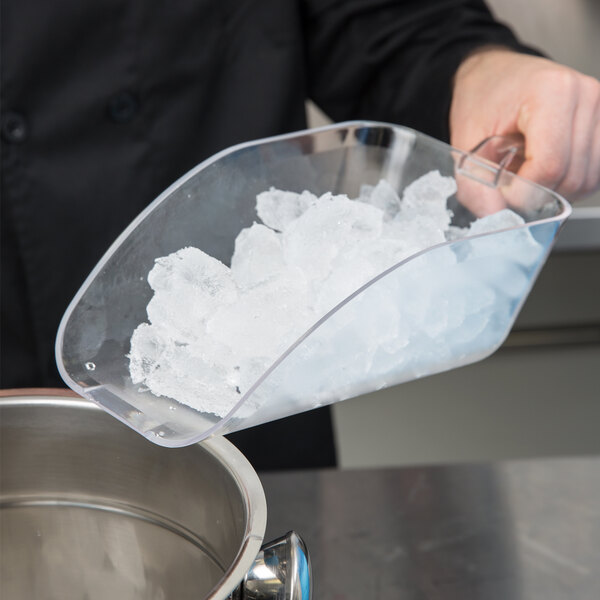 A person using a Cal-Mil clear plastic scoop to scoop ice into a bowl.