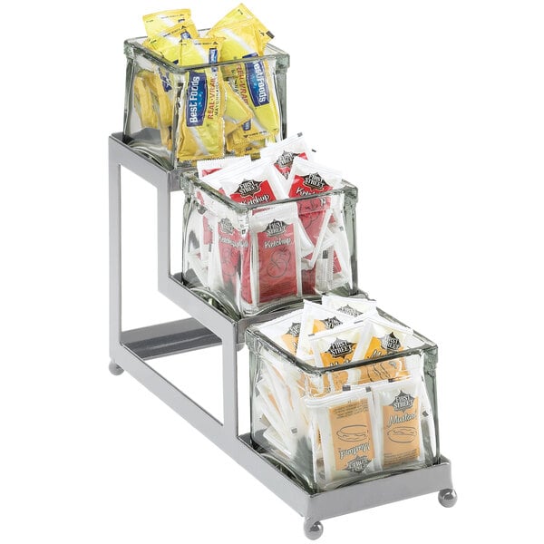 A Cal-Mil iron display rack holding three glass jars of condiments.