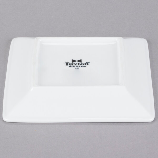 A white square Tuxton plate with black text that reads "TuxTrendz Santorini"